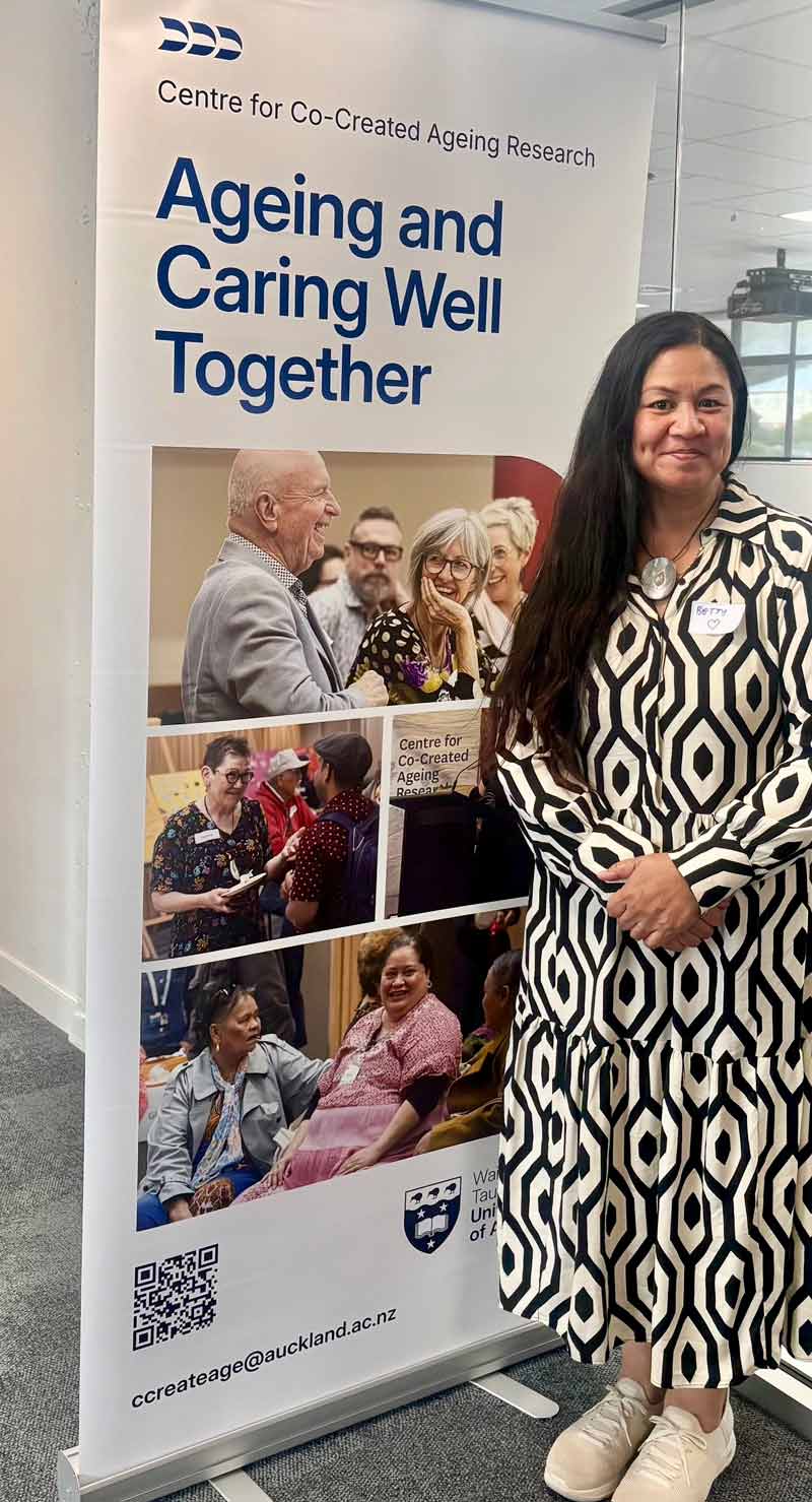 Betty standing in front of banner of Ageing and caring well together banner