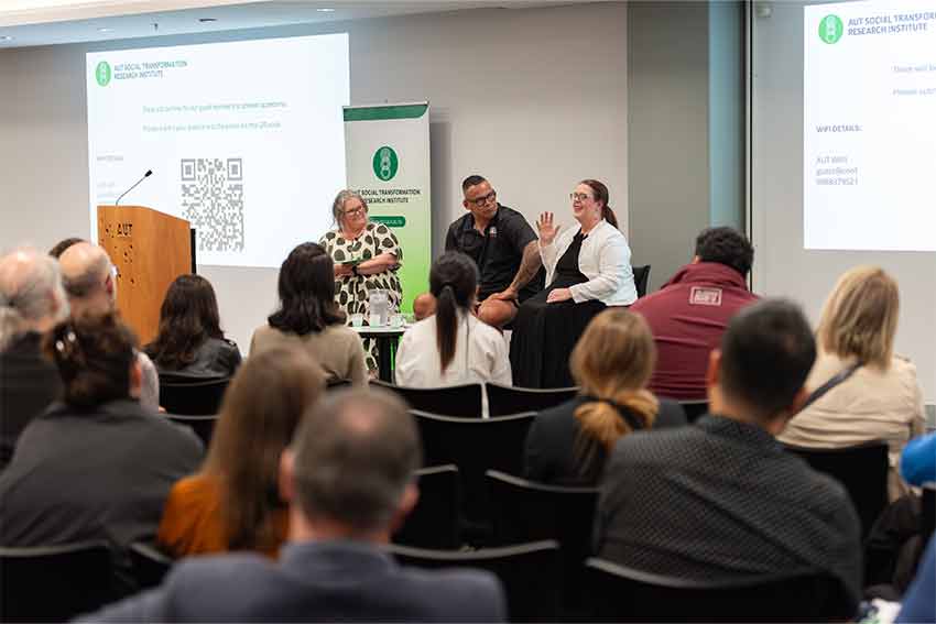 A panel of people standing in front of an audience